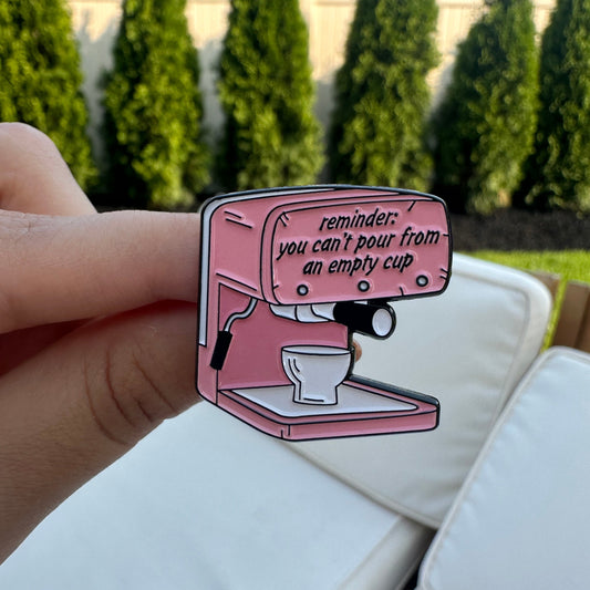 Pink coffee machine illustration held by a hand with a blurred outdoor background