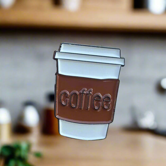 Belt buckle with 'coffee' engraving held by a hand against a light background