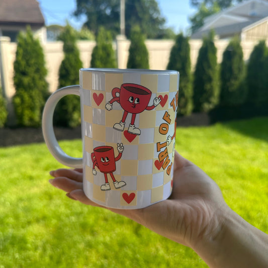 Hand holding a mug with cartoon character design outdoors